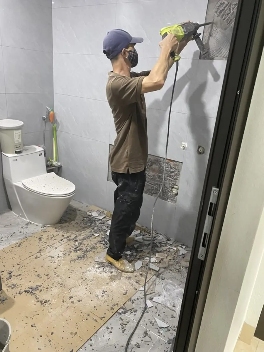 Tukang ASATURA membongkar keramik dinding kamar mandi lama sebelum renovasi